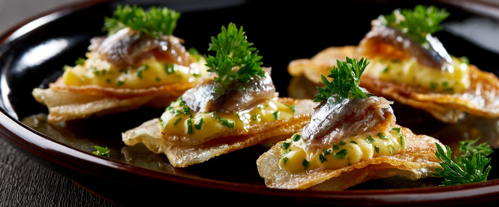 Boquerones op aardappelchip met citroen-peterseliemayo