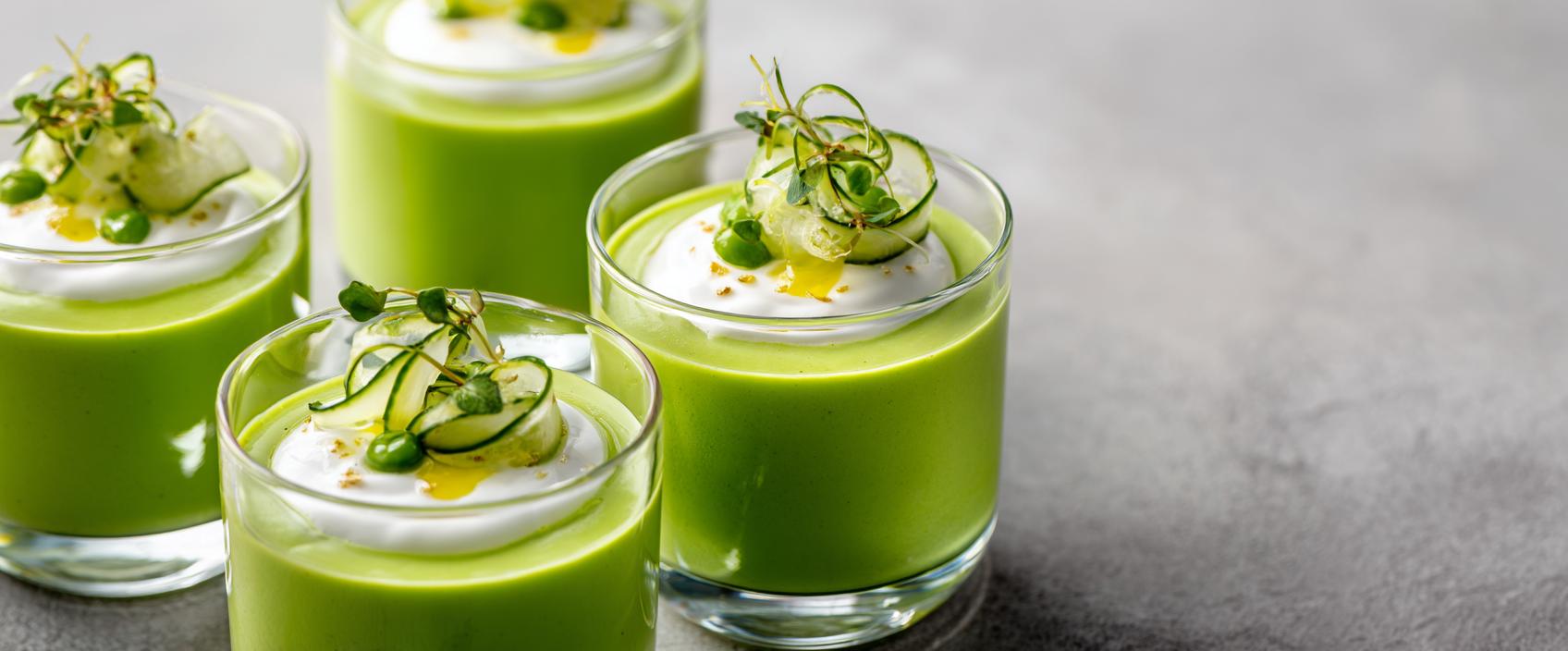 Koude doperwten-muntsoep in glas met room-yoghurt en muntblaadjesolie