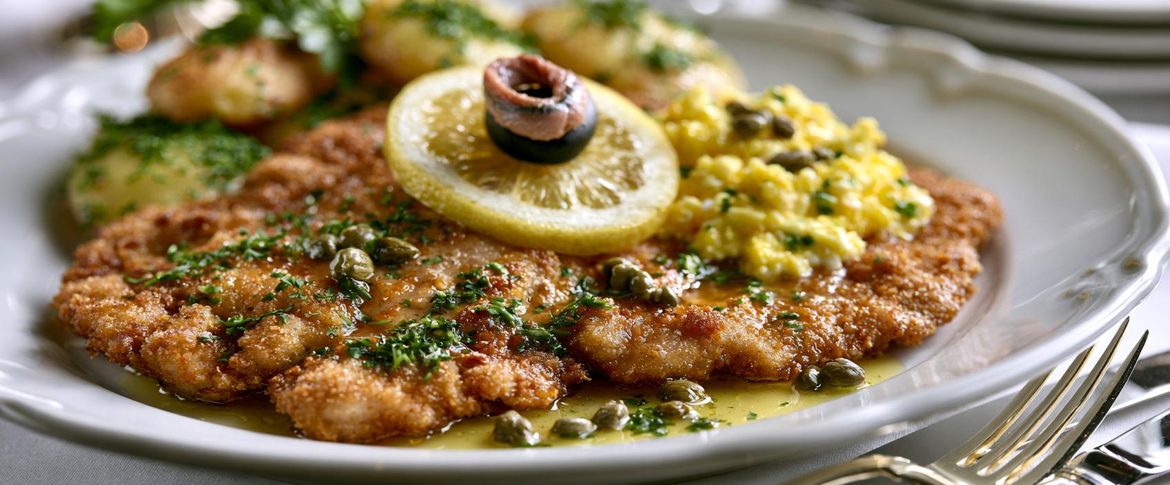 Varkensschnitzel à la viennoise met gebruinde boter, citroen, ansjovis en mimosa-ei