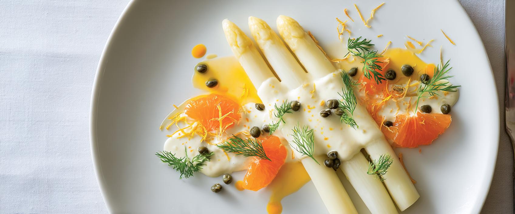 Witte asperges met sauce hollandaise légère, warme sinaasappelsaus en grote kappertjes